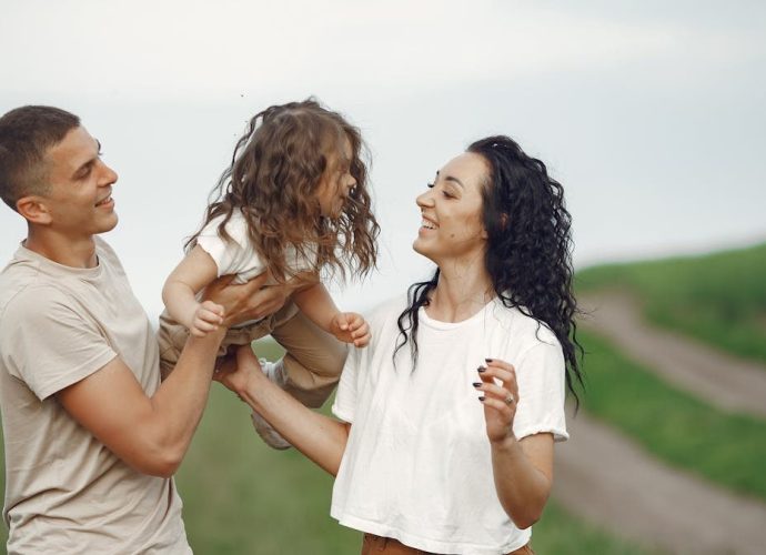 A joyful family moment outdoors with parents playing with their daughter.