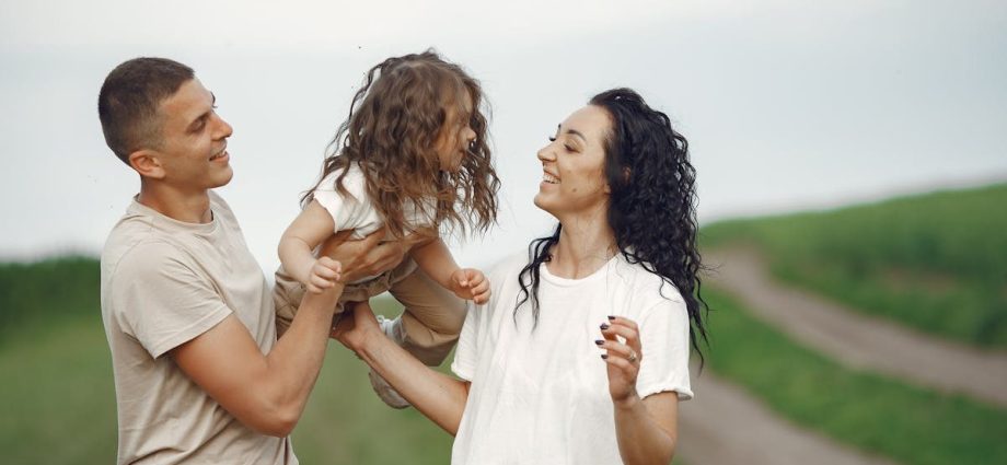A joyful family moment outdoors with parents playing with their daughter.