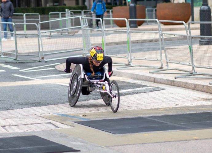 A dedicated athlete competes in a marathon using a racing wheelchair on city streets.