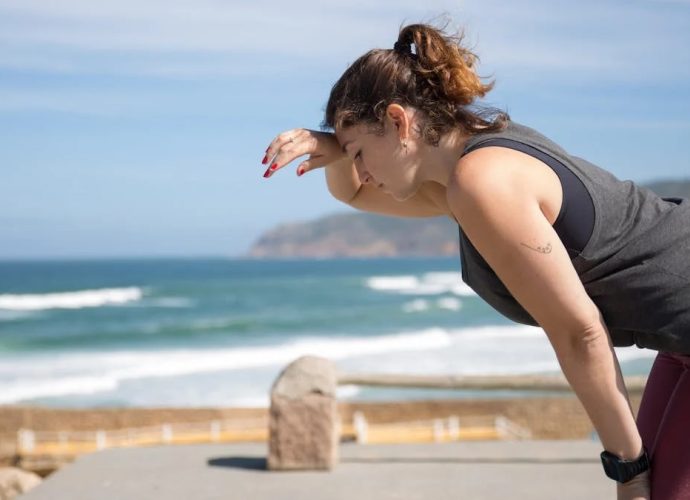 A woman rests after exercise, overlooking the ocean in Portugal's scenic seascape.